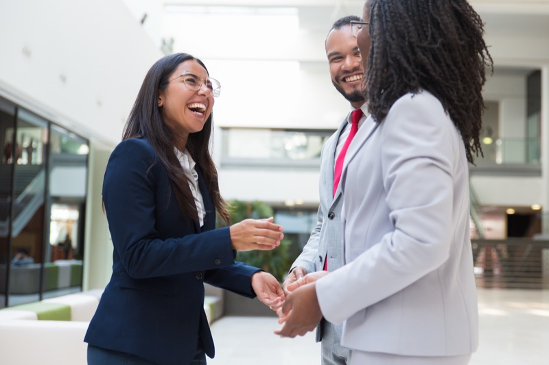 Smiling professionals greeting each other in an office lobby